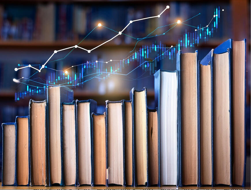 An image with books stacked on end on a shelf with their pages facing out and chart lines and graphs following the tops of the books